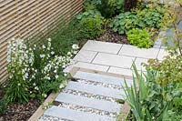 View of paved pathway in London garden, with raised stepping stones and gravel infill. By Earth Designs
 