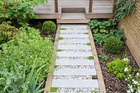 View of paved pathway in London garden, with raised stepping stones and gravel infill. By Earth Designs
