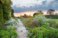 Path, made of slabs and setts of reclaimed York stone, surrounded by borders of seasonal spring interest at Malverleys, Hampshire, UK.
