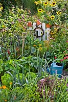 Mixed bed with a watering can, vegetables, herbs and flowers 