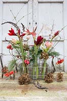 Floral arrangement in tray with milk bottles including Hippeastrum, crab apples, seedheads, holly and dried Hydrangea flowers. Styling: Marieke Nolsen
