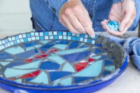 Woman placing mosaic tiles around the edge of the plate