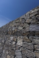 Tall gabion wall made of heavy duty galvanised wire and irregularly shaped, split olivine basalt.