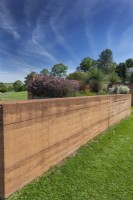 Rammed earth garden bed wall containing a planting of Australian native plants.