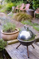 Small tripod barbecue on decking in a cottage garden in June