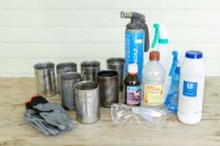 Gloves, goggles, tin cans, hydrogen peroxide, vinegar, table salt and blowtorch laid out on wooden surface