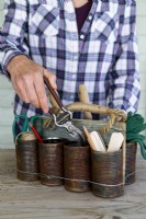 Woman placing secateurs into tin can caddy containing other items