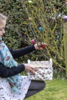 Child collecting a chocolate egg from a tree at Easter