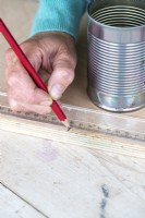 Woman marking the wooden board with a pencil and ruler