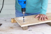 Woman drilling holes in the wooden board