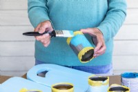 Woman painting the tin cans blue