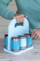 Woman using screwdriver to attach the cans to the wooden boards