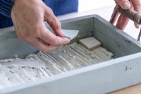 Placing a piece of tile in a tray to make a mosaic