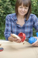 Woman taking wooden disc out of holesaw