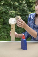 Woman gluing stack of wooden discs to the end of the post