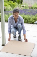 Woman laying down a sheet of cardboard on the floor