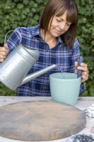 Woman pouring water into pot of powder grout