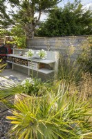 Outdoor kitchen with built-in wood storage in small modern garden