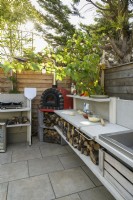 Outdoor kitchen with red pizza oven, sink hob and wood storage