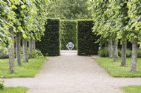 View down avenue of pleached limes to sculpture in the South Gardens. June