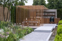 The Viking Friluftsliv Garden. A path flanked by a rill leads to a pergola built from iroko, for al fresco meals and outdoor kitchen. A multi-stemmed amelanchier shades a bed of grasses, astrantias, coneflowers, salvias, gaura and thalictrum.
