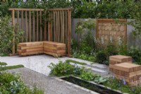 The Communication Garden. A tranquil refuge with woodland planting, a rectangular pool and flooring laid in planking and gravel. Wooden screens and cubes are made from sweet chestnut.