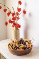 Bowl of cones and dried oranges with display of Physalis alkekengi