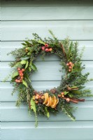 Scented christmas wreath made with thymus; laurel nobilis and rosmarinus and decorated with crab apples; cinnamon sticks and cones