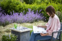 Woman sat next to stone slab table reading a magazine