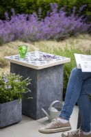 Stone slab table in a garden setting with woman reading magazine