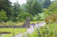 View from garden to stone wall and entrance with woodland beyond. Aberglasney Gardens Carmarthenshire Wales - June