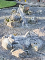 Figures of two naked males in gravel area. Sculptures by Jane Hazelwood. July