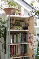 Conservatory bookcase filled with gardeners books, pots and gardening paraphanalia 