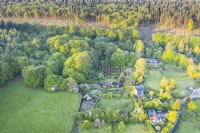 View taken by drone of the whole garden, showing its surroundings and edge of woodland