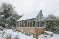 Gabriel Ash greenhouse in the snow with galvanised watering cans and containers
