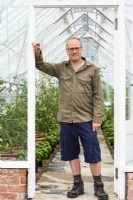 Man standing at entrance to greenhouse.