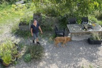 Anita van Zantvoort owner tea garden: 'Under the green heaven' and her dog. Overview with plants in containers.
