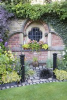 Decorative brick wall with window feature and path made of cobbles. Reclaimed material used. 