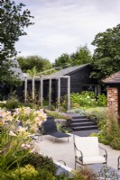 Contemporary garden designed by Andrea Newill with a sunken terrace of porcelain tiles framed by planting including Hemerocallis 'Catherine Woodbury' in July