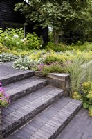 Steps of Lucca brick pavers softened with planting in July