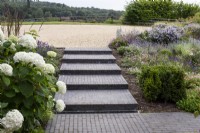 Steps of Lucca brick pavers leading from a gravel drive in July