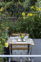 Landform, a small table on the balcony is surrounded by Helianthus 'Lemon Queen', Mentha x piperita f. citrata and grasses. 