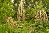 Four laminated bamboo structures surrounded by a pool filled with aquatic plants set in a woodland dell in the Guangzhou China: Guangzhou Garden, winnder of the best show garden award.