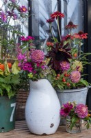 A jug, jar and a bucket full of cut flowers, including Dahlias, Echinacea, Anemones and rose hips.  