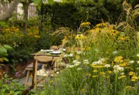 A border of autumnal perennials surrounding a dining area in the Parsley Box Garden.
