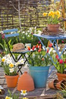 Relaxing area on decked patio with spring flowers in containers.