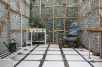Interior of greenhouse made from recycled glass bottles showing fountain and space to overwinter tender plants