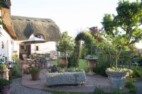 View of patio with containers and seating area outside thatched cottage 