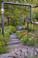 Stone steps through mixed autumn borders to the wooden seat. The M&G Garden, RHS Chelsea Flower Show 2021