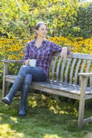 Woman sitting on a bench in front of Rudbeckias